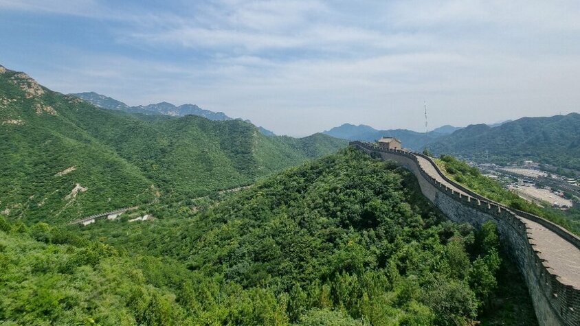 Blick über die Chinesische Mauer, die sich durch grüne Hügel und Berge windet – ein Höhepunkt von Jan Wengryns Zeit in China.