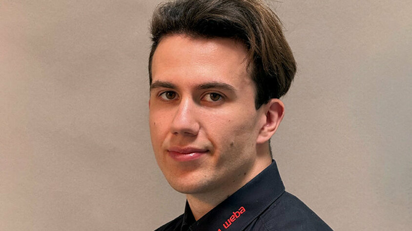 Porträtfoto von Michal Urbuś, IT-Techniker bei weba Werkzeugbau, in schwarzem Hemd mit rotem weba-Logo vor neutralem Hintergrund.