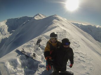 Tomáš Novotný beim Snowboarden in den Bergen mit Blick auf verschneite Gipfel