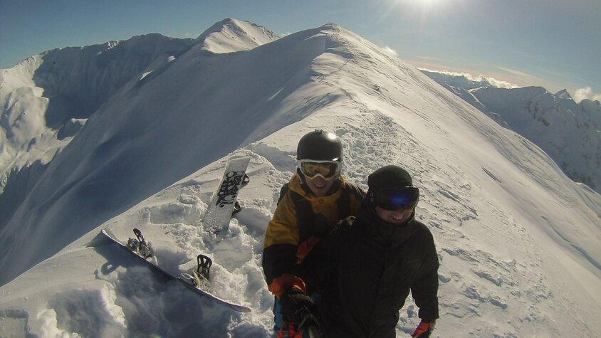 Tomáš Novotný beim Snowboarden in den Bergen mit Blick auf verschneite Gipfel