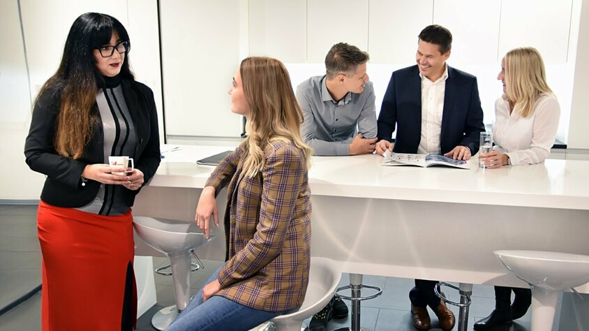 Angestellte der weba Werkzeugbau stehen in der Kaffeeküche und unterhalten sich.