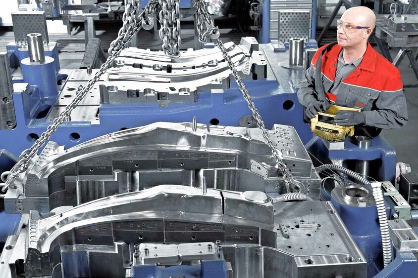 Nástrojářský technik obsluhuje jeřábový systém v nástrojárně při montáži aktivních částí nástroje pro tváření za tepla ve společnosti weba Werkzeugbau.