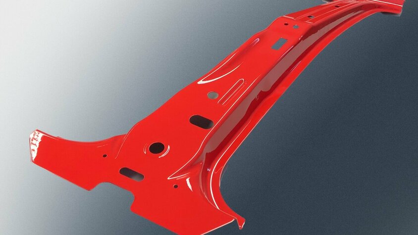 Metallisches Bauteil aus dem Prototypenbau von weba Deutschland, lackiert in Rot, mit komplexer Geometrie und mehreren Durchbrüchen, vor einem dunklen Hintergrund.