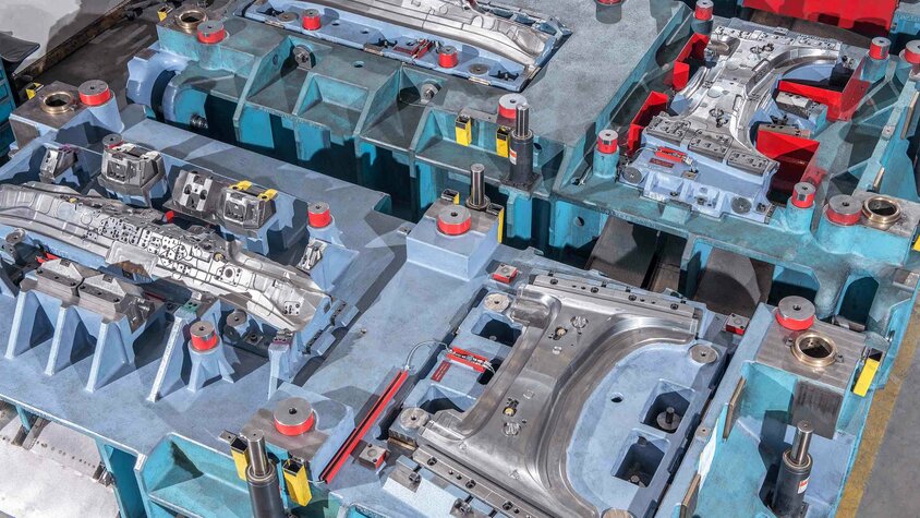 Ausschnitt eines Linienwerkzeugs mit mehreren Umform- und Schneidstationen für die Kaltumformung von Karosserieteilen.