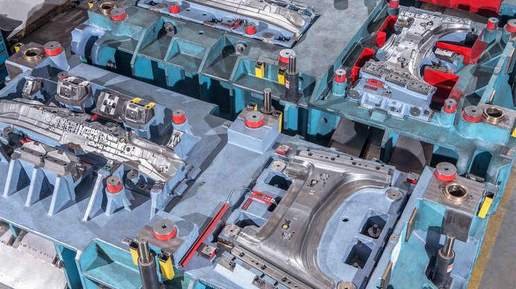 Ausschnitt eines Linienwerkzeugs mit mehreren Umform- und Schneidstationen für die Kaltumformung von Karosserieteilen.