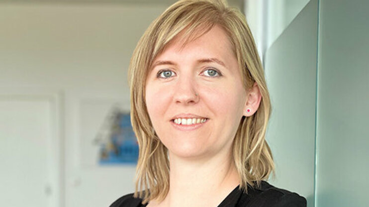 Porträt von Tanja Burghuber, Personalmanagerin bei weba Werkzeugbau, entspannt an einer Milchglaswand in Dietach lehnend, mit einem professionellen und freundlichen Ausdruck, betont durch die weiche Beleuchtung und den verschwommenen Hintergrund. Das Foto wird im Kontaktbereich der Stellenangebote in Steyr von weba Werkzeugbau verwendet.