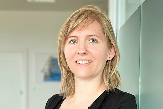 Porträt von Tanja Burghuber, Personalmanagerin bei weba Werkzeugbau, entspannt an einer Milchglaswand in Dietach lehnend, mit einem professionellen und freundlichen Ausdruck, betont durch die weiche Beleuchtung und den verschwommenen Hintergrund. Das Foto wird im Kontaktbereich der Stellenangebote in Steyr von weba Werkzeugbau verwendet.