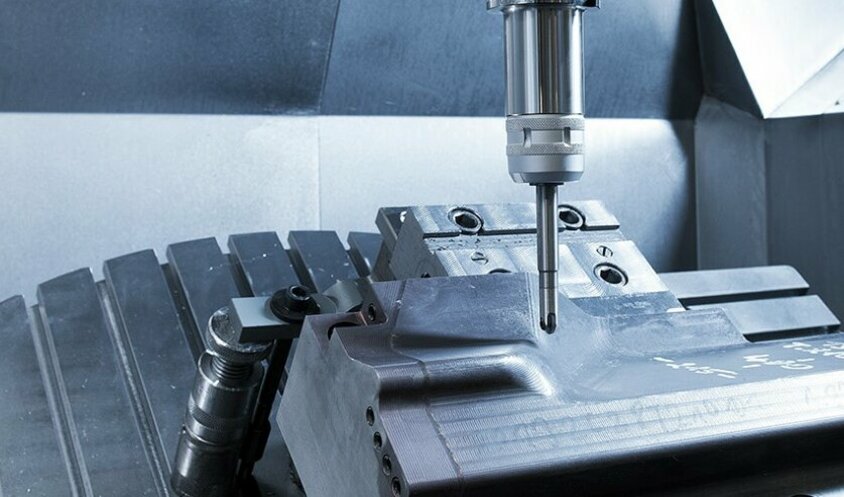 Innenaufnahme eines CNC-Bearbeitungszentrums bei der Lohnfertigung, während es einen Stahleinsatz fräst.