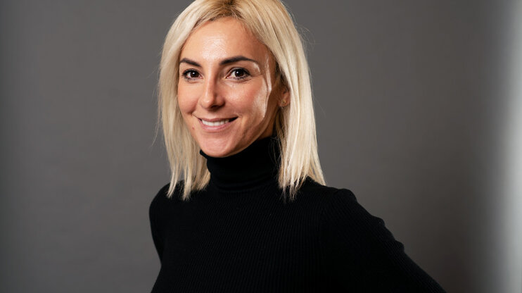  Porträt von Ivana Vujica, strategische Einkäuferin bei weba, vor einem grauen Hintergrund.