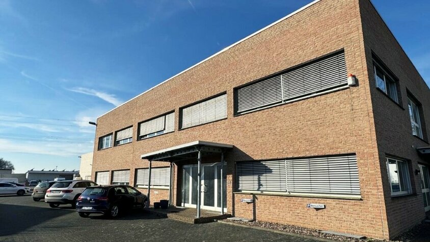 Das Firmengebäude der weba Deutschland GmbH, einem Experten für Prototypenbau, bei sonnigem Wetter mit Parkplätzen und moderner Architektur.