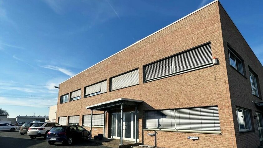 Das Firmengebäude der weba Deutschland GmbH, einem Experten für Prototypenbau, bei sonnigem Wetter mit Parkplätzen und moderner Architektur.