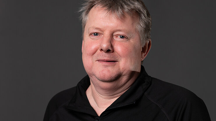 Klaus Postlbauer, Prozessleiter im Werkzeugbau bei weba, lächelt in die Kamera vor neutralem Hintergrund. Mit ruhiger Ausstrahlung und einem leichten Lächeln blickt er in die Kamera. Das Bild vermittelt Kompetenz und Bodenständigkeit – passend zu seiner langjährigen Verbindung mit weba Werkzeugbau.