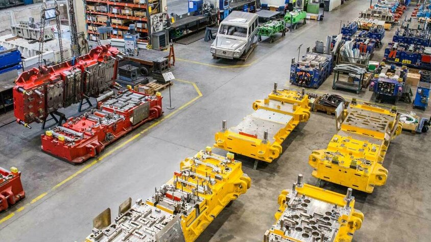 Montagehalle von weba Werkzeugbau, bei der im Vordergrund große Presswerkzeuge und im Hintergrund Bearbeitungszentren zu erkennen sind.