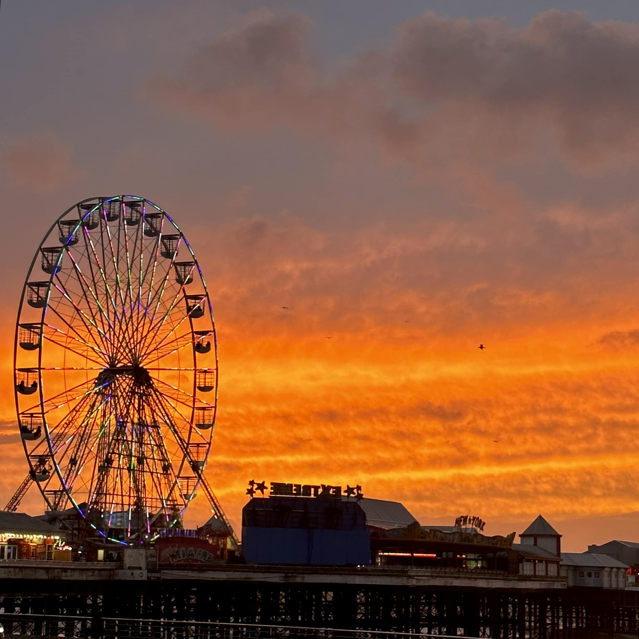 Riesenrad im Freizeitpark bei Sonnenuntergang in Blackpool mit leuchtendem Himmel
