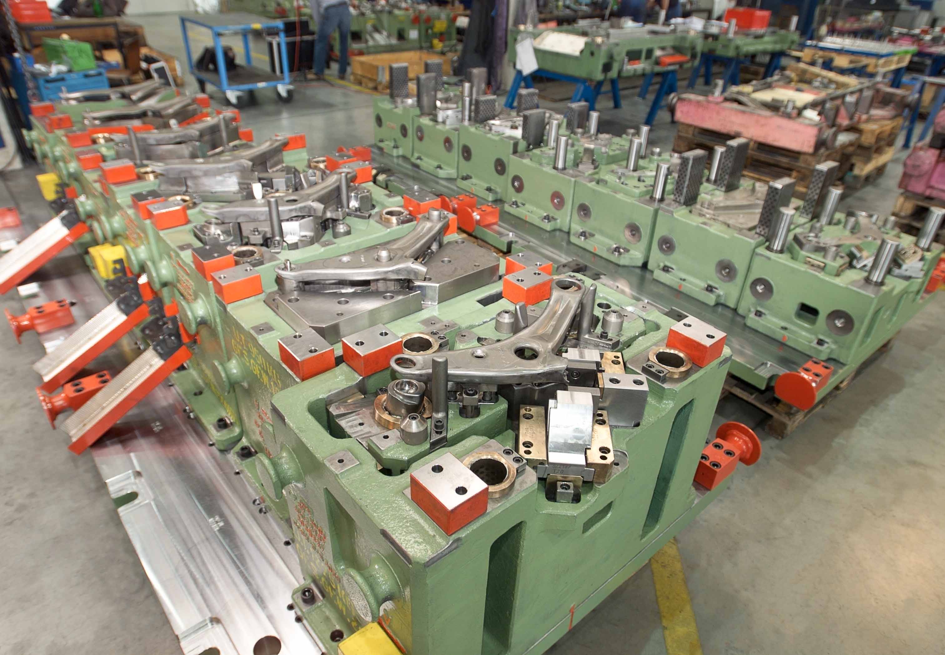Transfer tool for a control arm in automotive production; complex tool setup with multiple forming stations and mechanical units in the weba Werkzeugbau facility.